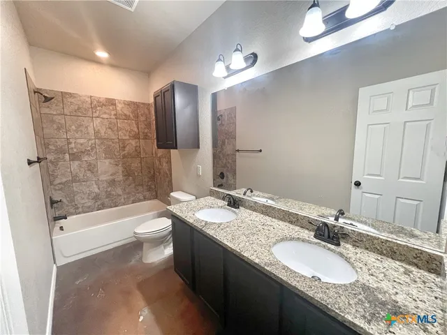 a bathroom with a granite countertop sink toilet and mirror