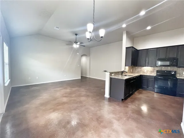 a kitchen with stainless steel appliances granite countertop a stove top oven a sink and a refrigerator