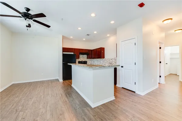 a open kitchen with white cabinets appliances and wooden floor