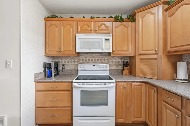a kitchen with granite countertop a sink a stove and cabinets