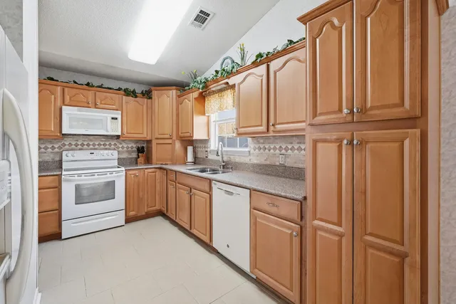 a kitchen with granite countertop white cabinets and white appliances