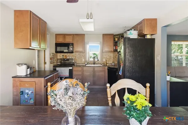 a kitchen with stainless steel appliances granite countertop a refrigerator a stove a microwave oven with a dining table and chairs