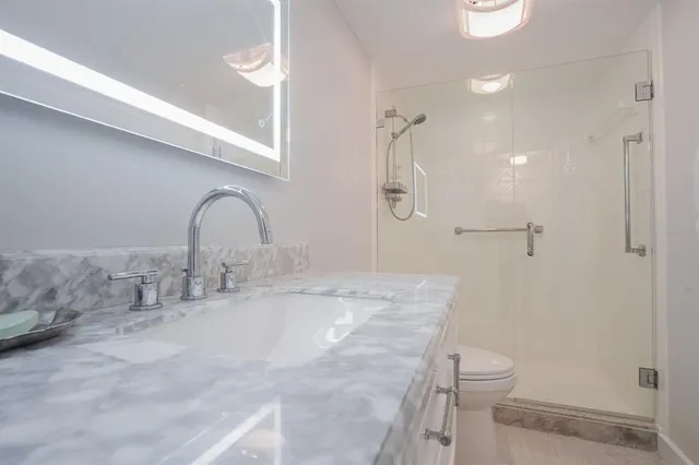 a view of a hallway with wooden floor and a bathroom