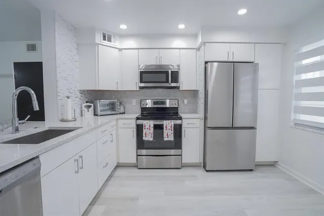 a kitchen with stainless steel appliances granite countertop a stove a sink and a microwave