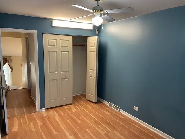 en empty room with closet and a chandelier fan