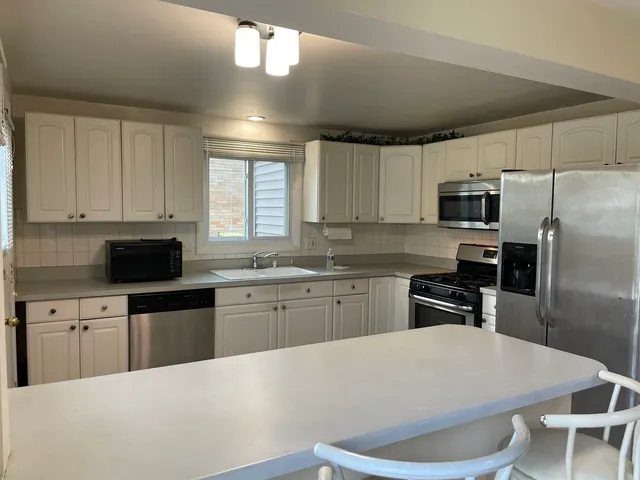 a kitchen with granite countertop a refrigerator stove microwave and sink