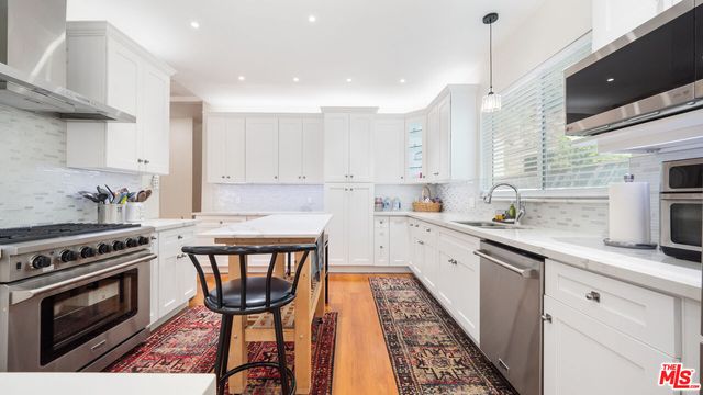 a kitchen with stainless steel appliances granite countertop a stove a sink dishwasher and a microwave oven with white cabinets