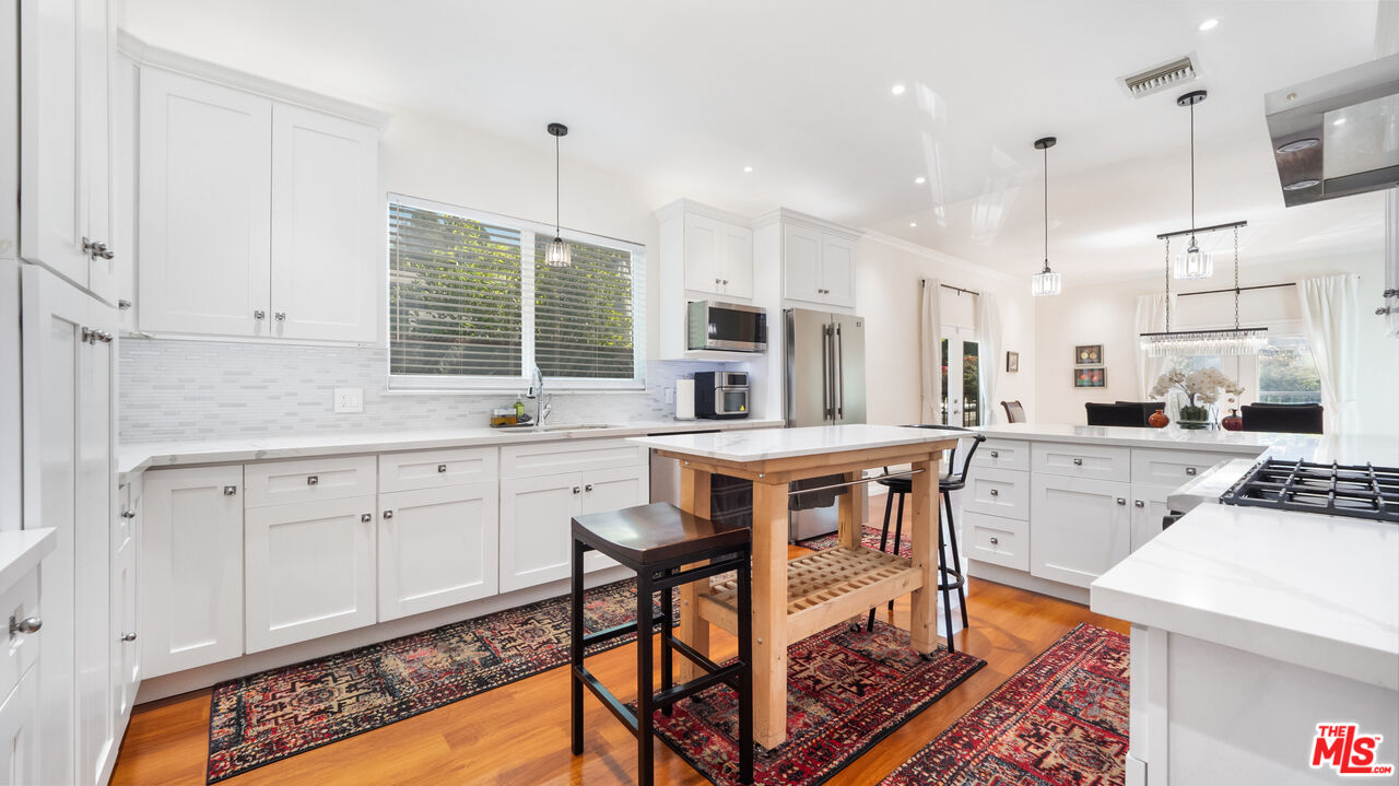 2655 Saxon Drive Los Angeles, CA 90065 - Photo 15 of 40 a kitchen with stainless steel appliances kitchen island granite countertop a table chairs sink and cabinets