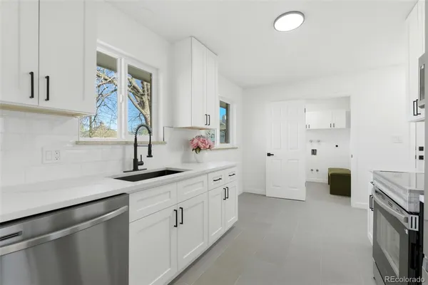 a kitchen with white cabinets and sink