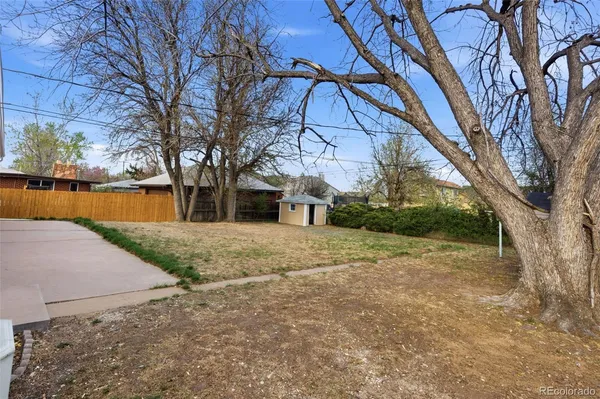 a backyard of a house with large trees and parked