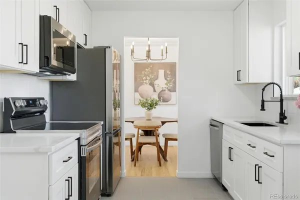 a kitchen with stainless steel appliances granite countertop a white stove top oven a sink a dining table and chairs with wooden floor