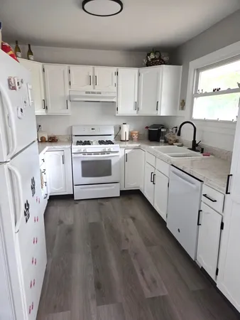 a kitchen with white cabinets white appliances and sink