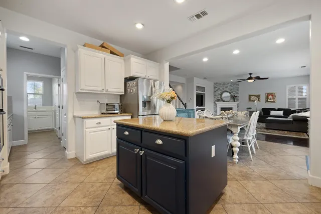 a dining room with stainless steel appliances kitchen island granite countertop a table chairs and a refrigerator