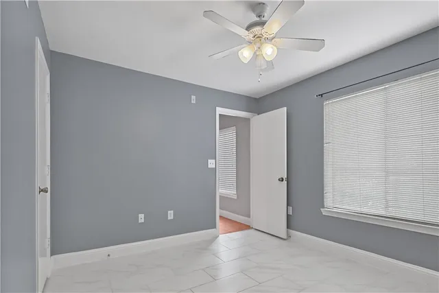 a view of an empty room and chandelier fan
