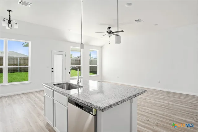 a kitchen with stainless steel appliances granite countertop a sink a stove and a granite counter top