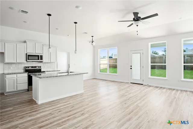 a view of kitchen with refrigerator microwave and stove top oven
