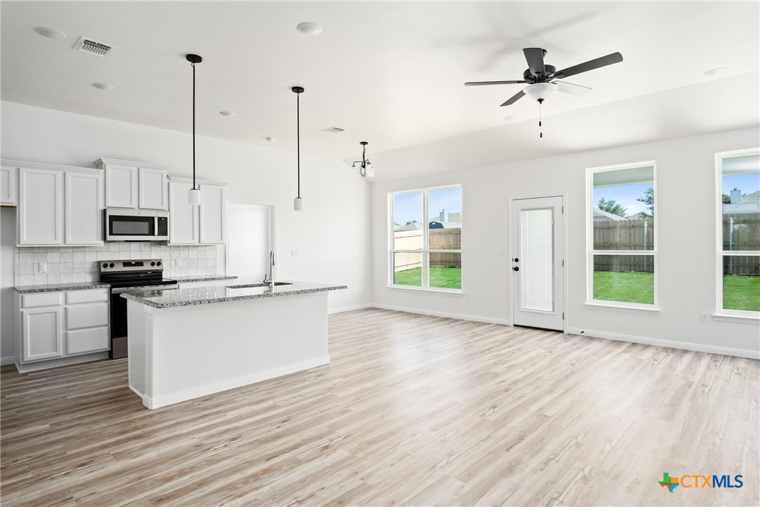 1013 Lago Azul Lane Temple, TX 76504 - Photo 9 of 32 a kitchen with stainless steel appliances kitchen island wooden floors granite counter tops and a window