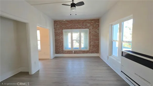 a view of an empty room with a window and wooden floor