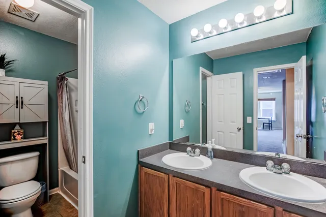a bathroom with a granite countertop sink a toilet and a mirror