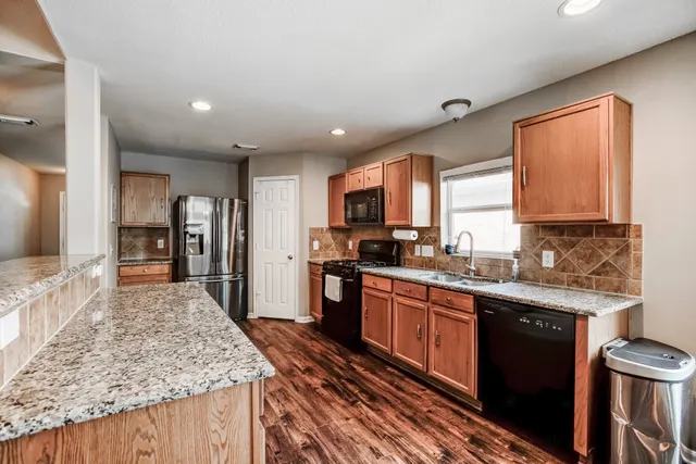 a kitchen with stainless steel appliances granite countertop sink stove refrigerator and cabinets