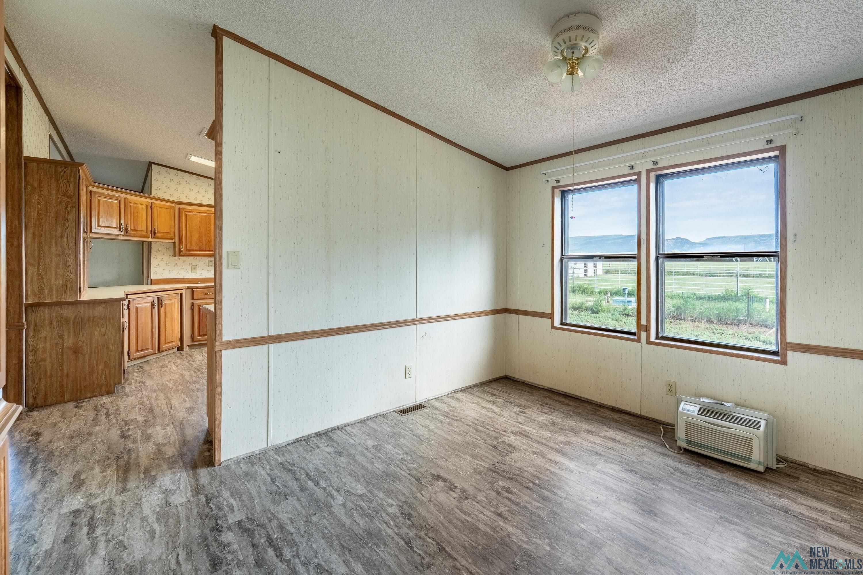35234 Highway 87 Raton, NM 87740 - Photo 44 of 90 Empty room featuring wood finished floors, crown molding, a textured ceiling, and a wall mounted AC