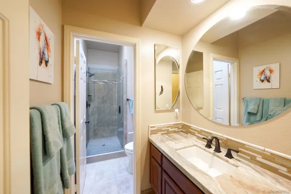 a bathroom with a granite countertop double vanity sink mirror and shower