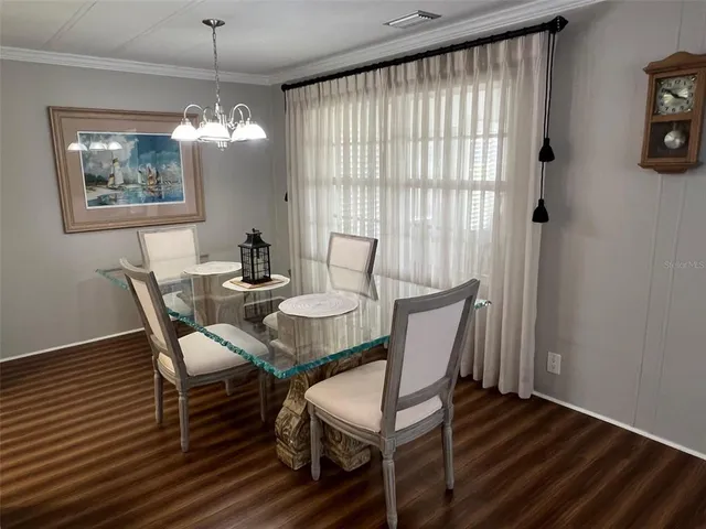 a view of a dining room with furniture a chandelier and wooden floor