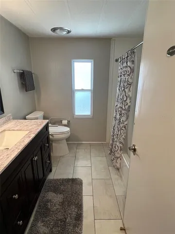 a bathroom with a granite countertop sink a toilet and shower