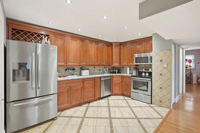 a kitchen with granite countertop stainless steel appliances a refrigerator cabinets and wooden floor