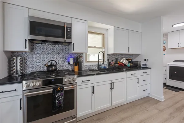 a kitchen with granite countertop white cabinets stainless steel appliances and a sink