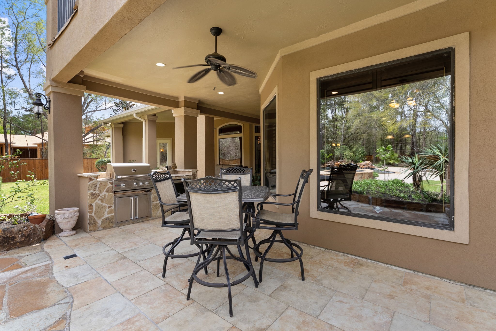 3907 Rayford Road Spring, TX 77386 - Photo 30 of 38 The covered patio is designed for entertaining, featuring tile flooring, a ceiling fan, and a fully equipped outdoor kitchen with stone surround, built-in grill, beverage fridge, and granite countertops.