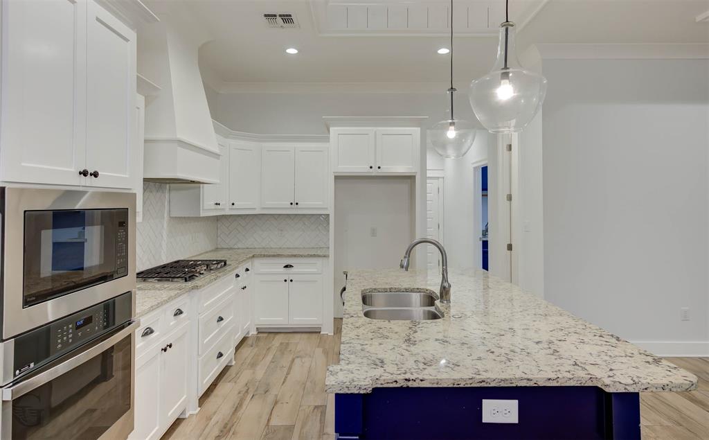 605 Meridian Way Benton, LA 71006 - Photo 11 of 29 Modern kitchen featuring white cabinetry, light granite countertops, a herringbone tile backsplash, stainless steel appliances, and wood-finish flooring