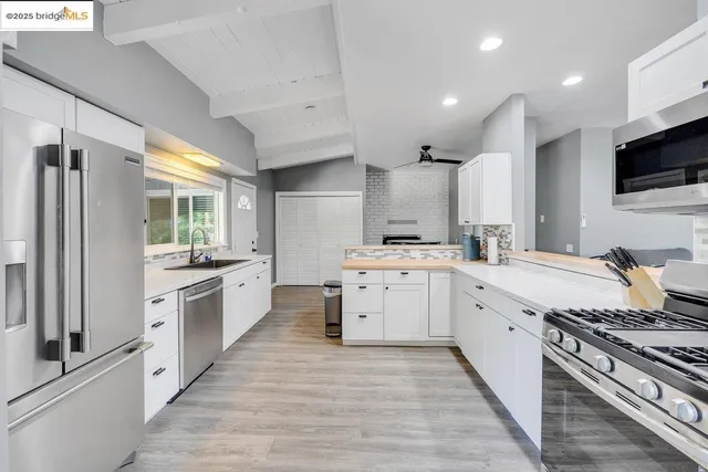 a large kitchen with granite countertop a large counter top stainless steel appliances and cabinets