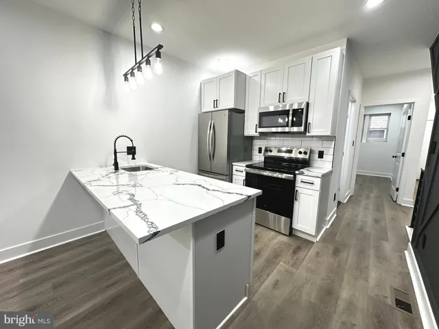 a kitchen with kitchen island a sink stove refrigerator and cabinets