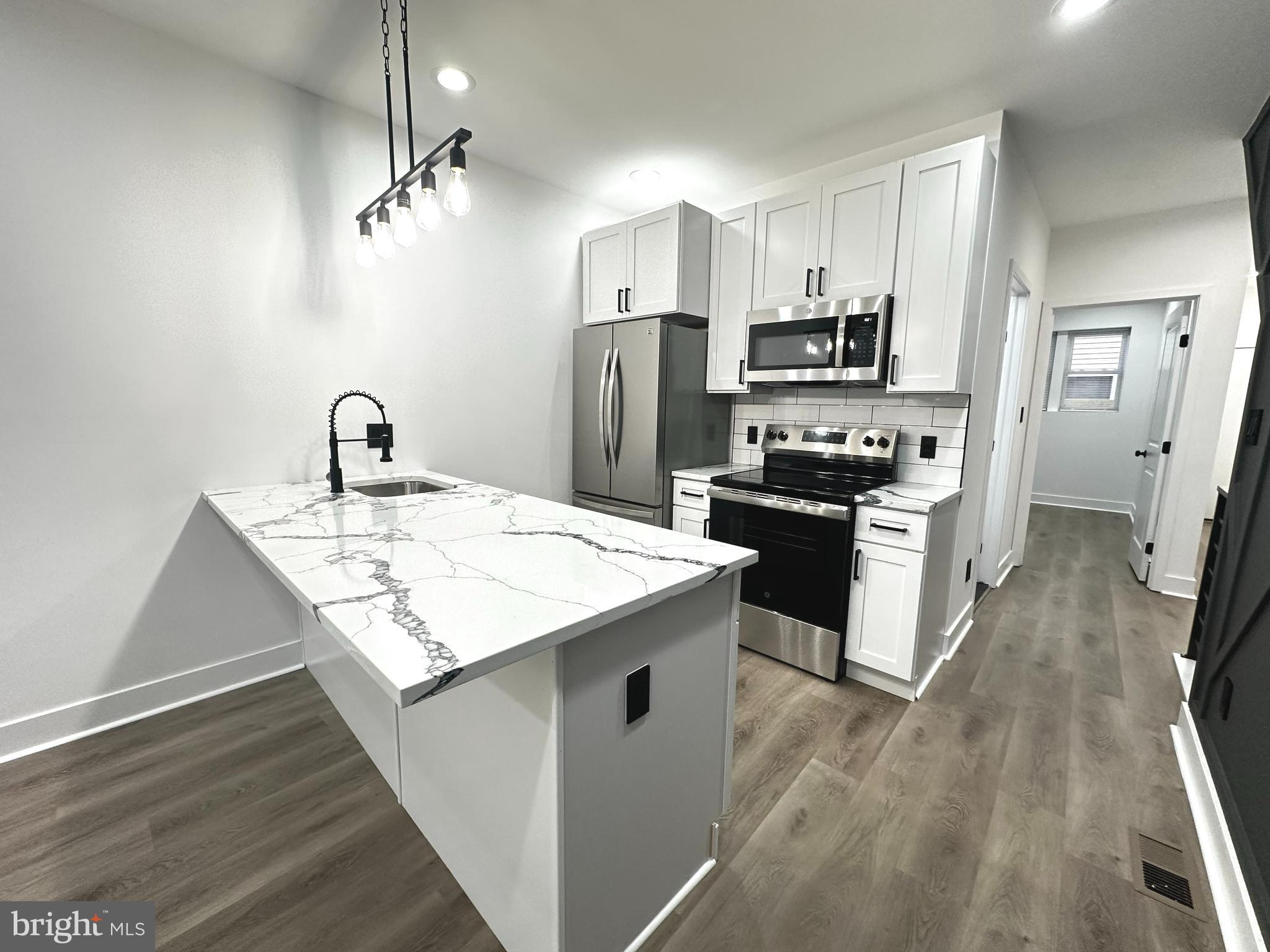 1015 South 6th Street, Unit 1 Philadelphia, PA 19147 - Photo 3 of 18 a kitchen with kitchen island a sink stove refrigerator and cabinets