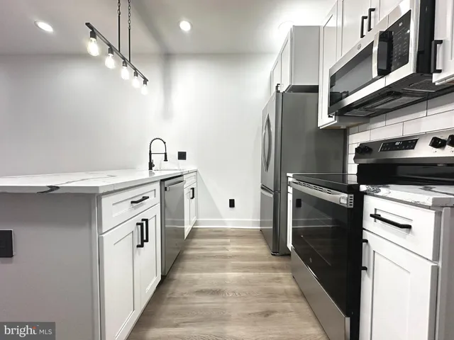 a kitchen with stainless steel appliances granite countertop a refrigerator a stove and a sink