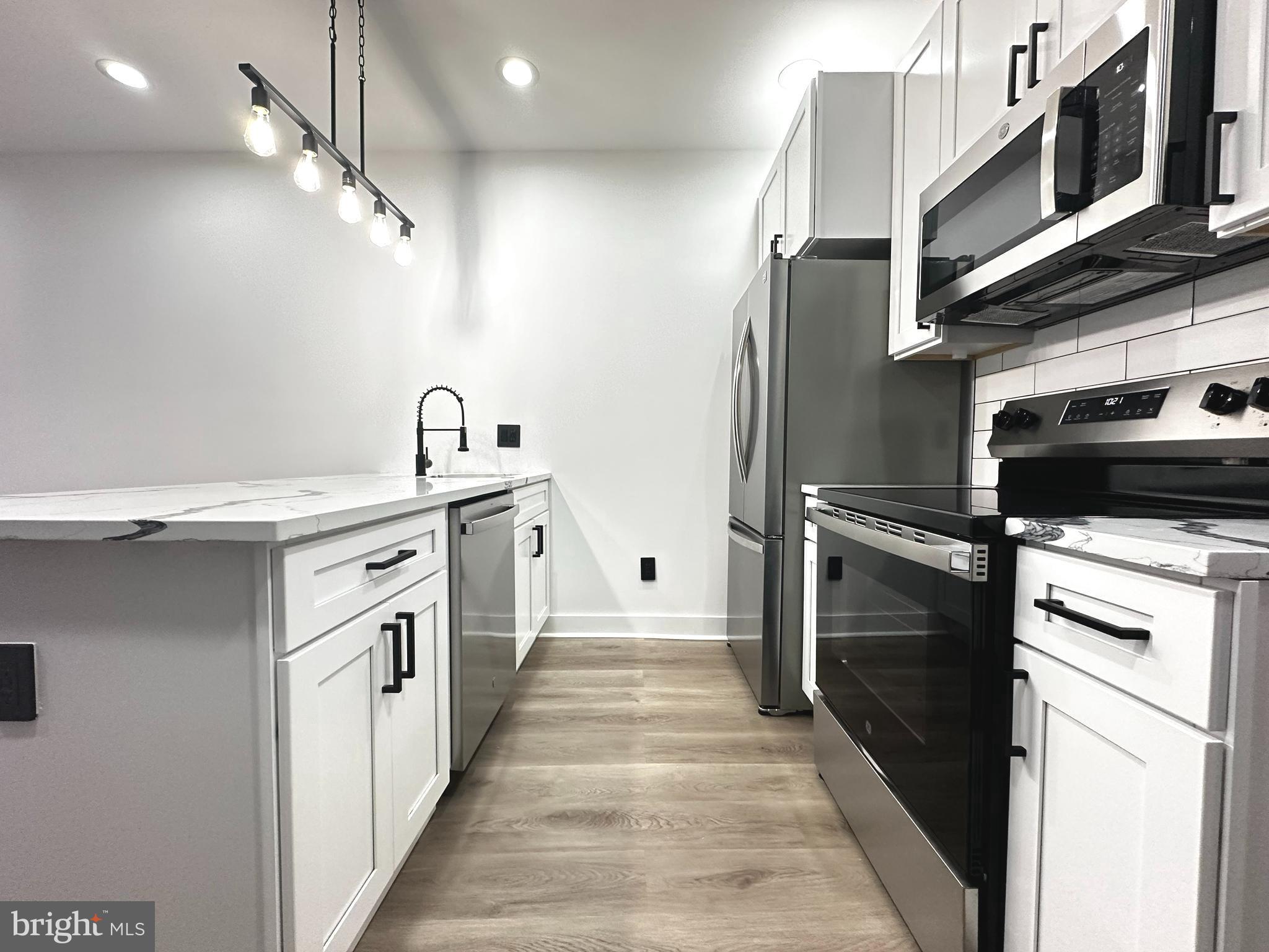 1015 South 6th Street, Unit 1 Philadelphia, PA 19147 - Photo 4 of 18 a kitchen with stainless steel appliances granite countertop a refrigerator a stove and a sink