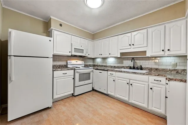 a kitchen with granite countertop white cabinets and white appliances