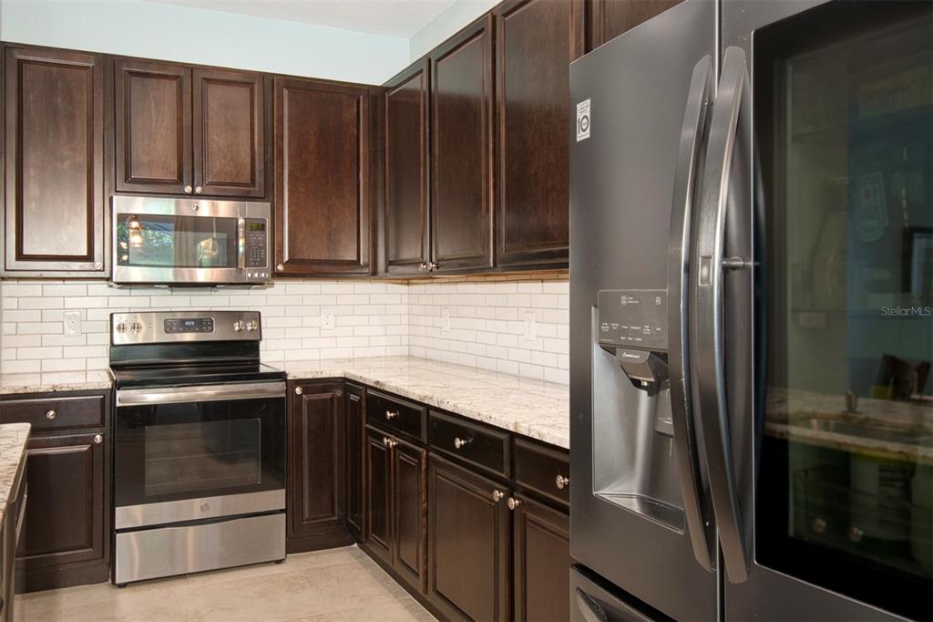 1111 Spruce Ridge Court Minneola, FL 34715 - Photo 11 of 34 a kitchen with granite countertop a refrigerator stove and microwave