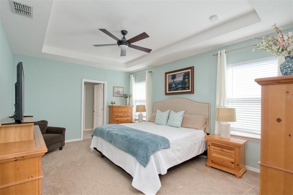 1111 Spruce Ridge Court Minneola, FL 34715 - Photo 13 of 34 a bedroom with a bed and a chandelier