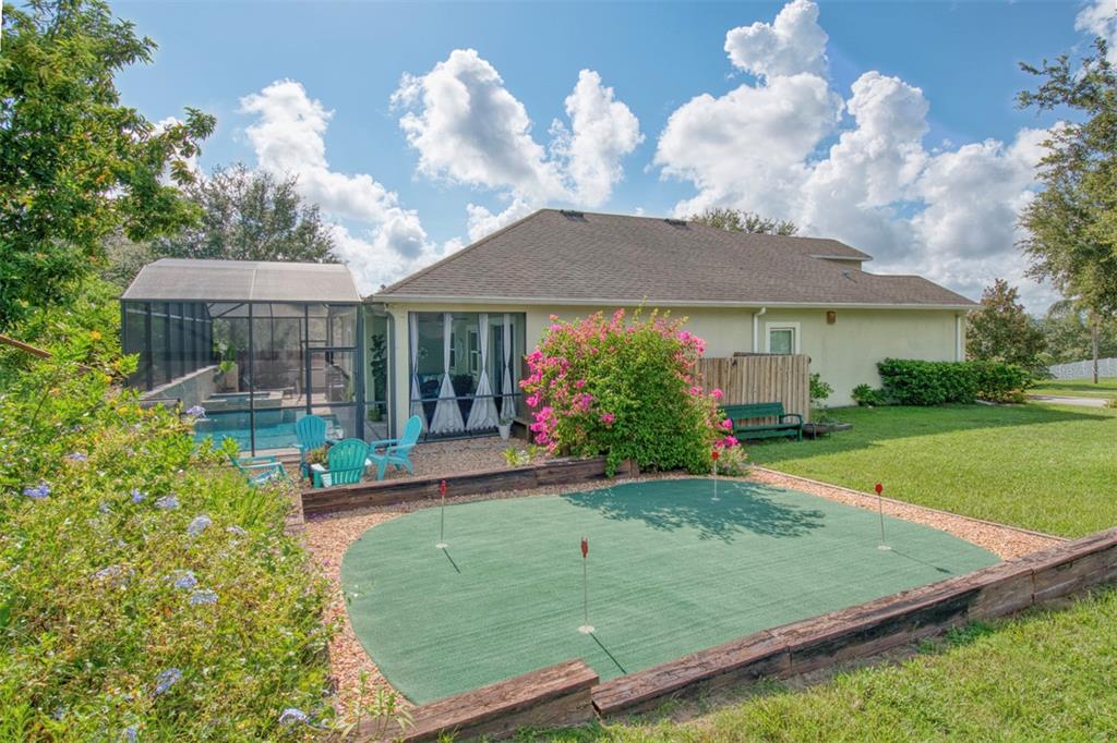 1111 Spruce Ridge Court Minneola, FL 34715 - Photo 28 of 34 a view of a white house with a yard potted plants and a large tree