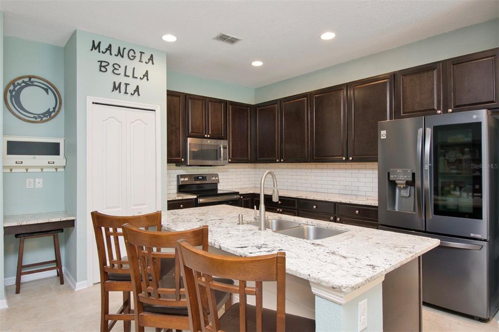 1111 Spruce Ridge Court Minneola, FL 34715 - Photo 10 of 34 a kitchen with granite countertop a table chairs stove and refrigerator