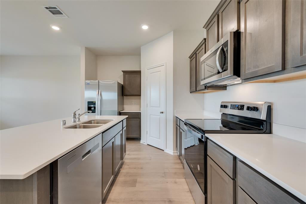 1428 Millstead Rill Drive Caddo Mills, TX 75135 - Photo 5 of 24 a kitchen with stainless steel appliances granite countertop a sink stove and refrigerator