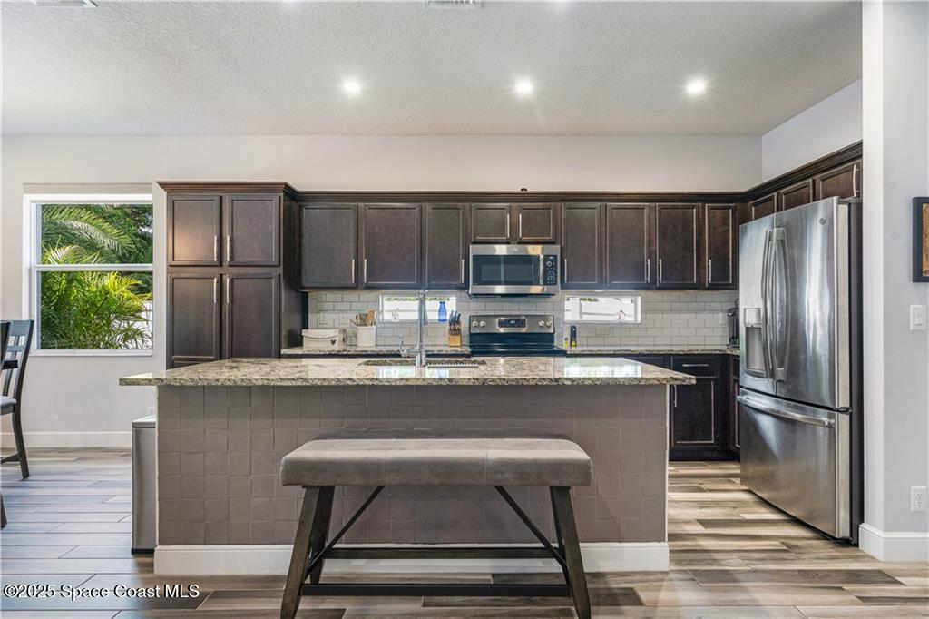 Undisclosed Address Vero Beach, FL 32966 - Photo 19 of 36 a kitchen with kitchen island a stove a refrigerator and a oven with wooden floor