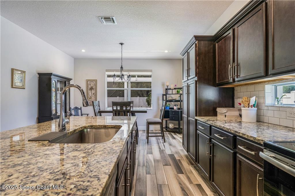 Undisclosed Address Vero Beach, FL 32966 - Photo 24 of 36 a kitchen with stainless steel appliances granite countertop a sink dishwasher a stove and a refrigerator with wooden floor