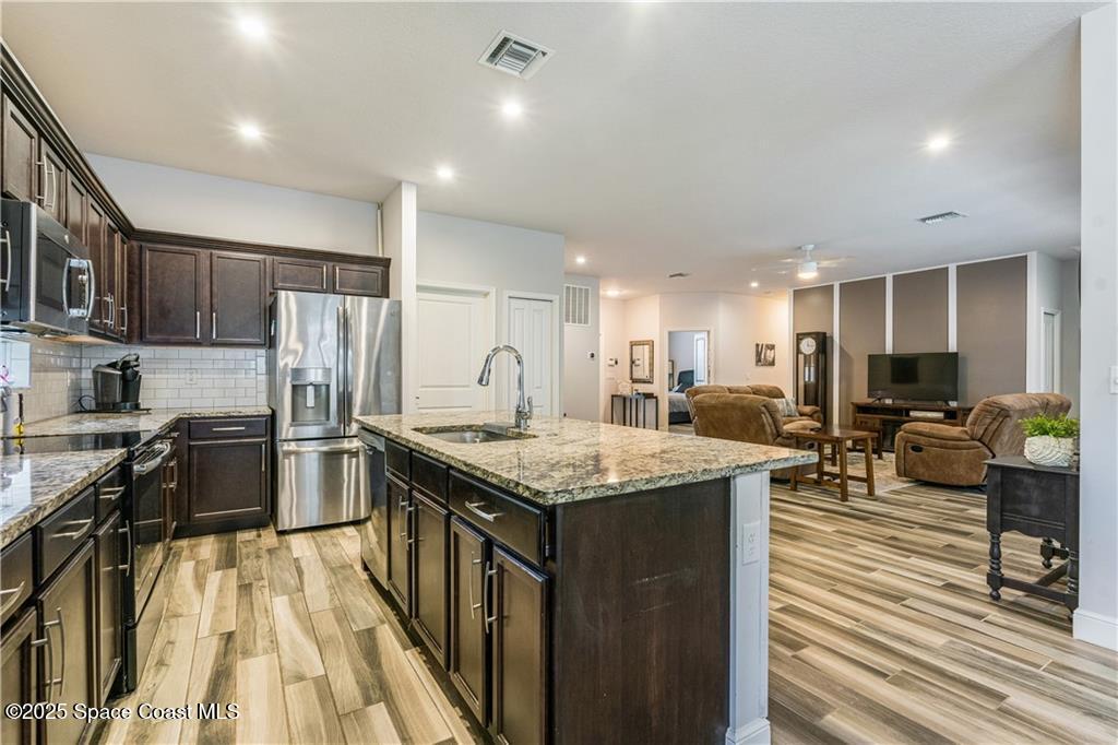 Undisclosed Address Vero Beach, FL 32966 - Photo 4 of 36 a kitchen with stainless steel appliances granite countertop a kitchen island a stove a refrigerator a sink a dining table and chairs with wooden floor