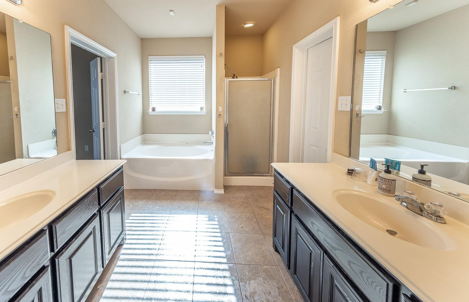 5211 Harvard Street Lubbock, TX 79416 - Photo 16 of 31 a bathroom with a double vanity sink a mirror and a bathtub