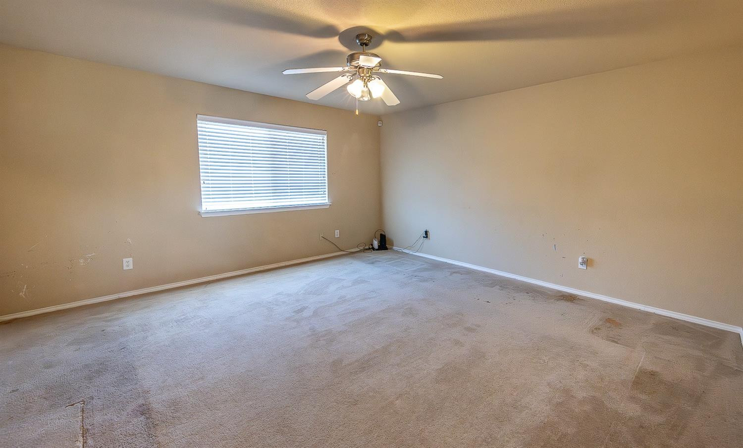 5211 Harvard Street Lubbock, TX 79416 - Photo 20 of 31 an empty room with a chandelier fan and windows