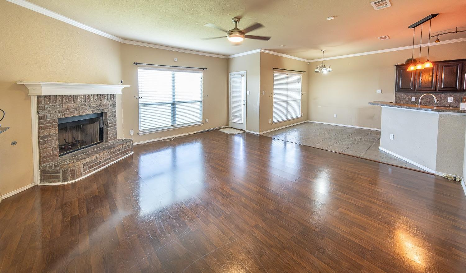 5211 Harvard Street Lubbock, TX 79416 - Photo 2 of 31 an empty room with wooden floor a fireplace and windows