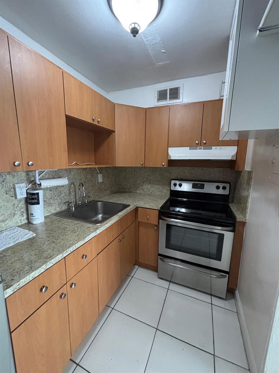 11005 Southwest 1st Street, Unit 302 Sweetwater, FL 33174 - Photo 7 of 9 a kitchen with stainless steel appliances granite countertop a sink stove and cabinets